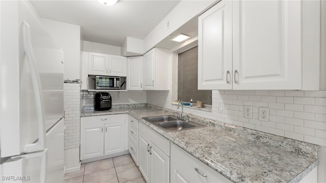 kitchen featuring white cabinetry, sink, tasteful backsplash, white refrigerator, and light tile patterned floors