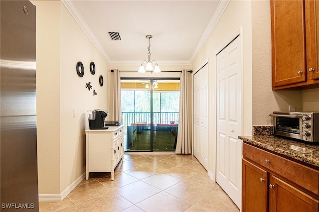 kitchen with stainless steel refrigerator, hanging light fixtures, a notable chandelier, light tile patterned flooring, and ornamental molding