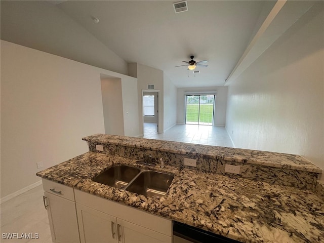 kitchen featuring white cabinetry, ceiling fan, sink, dark stone countertops, and lofted ceiling