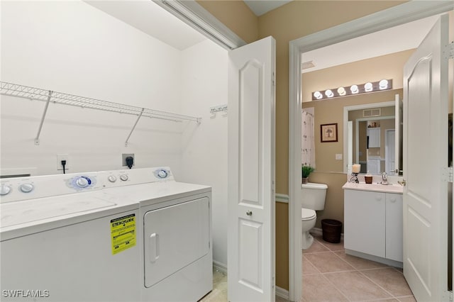 laundry area featuring sink, washing machine and dryer, and light tile patterned flooring