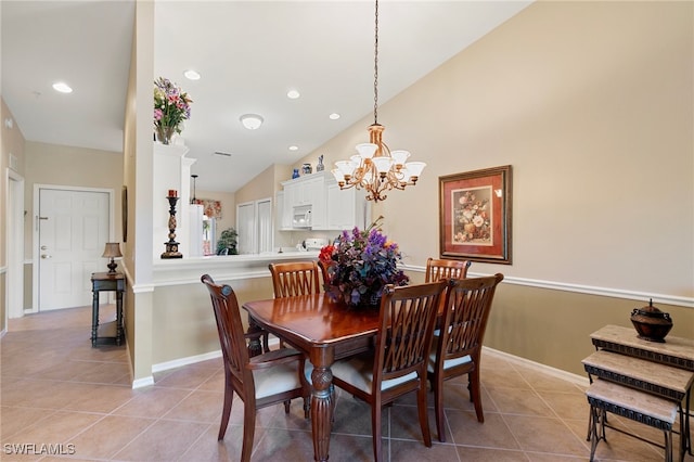 tiled dining area featuring an inviting chandelier and vaulted ceiling