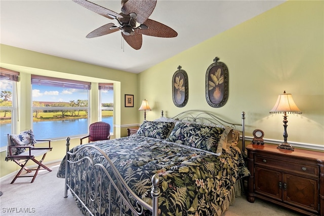 bedroom featuring a water view, light colored carpet, and ceiling fan