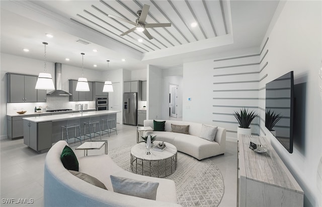 living room with a raised ceiling, ceiling fan, and sink