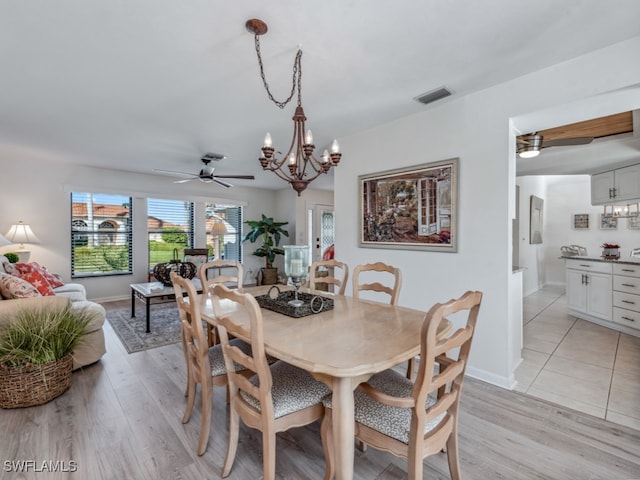 dining area with ceiling fan with notable chandelier and light hardwood / wood-style flooring