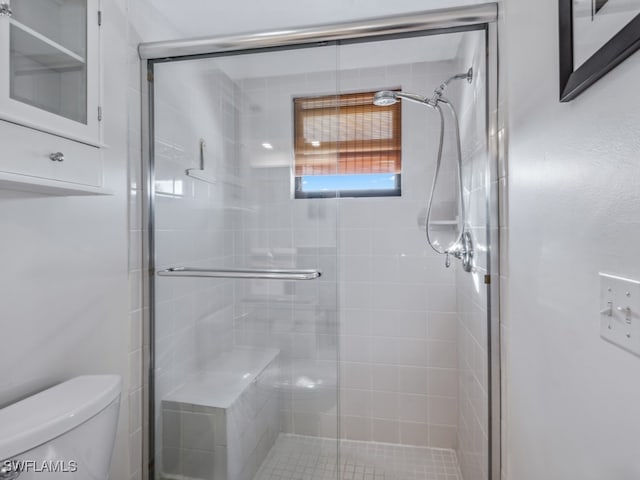 bathroom featuring a shower with shower door and toilet