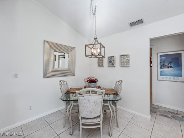 dining room with light tile patterned flooring, vaulted ceiling, and an inviting chandelier