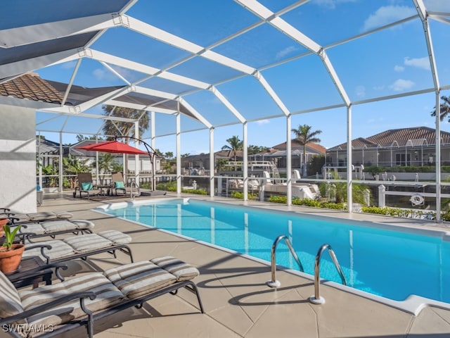 view of pool with glass enclosure and a patio