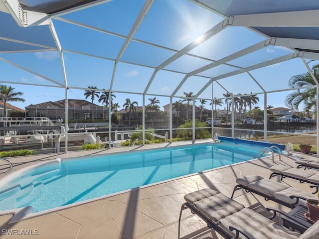 view of swimming pool with a patio area, a lanai, and a water view