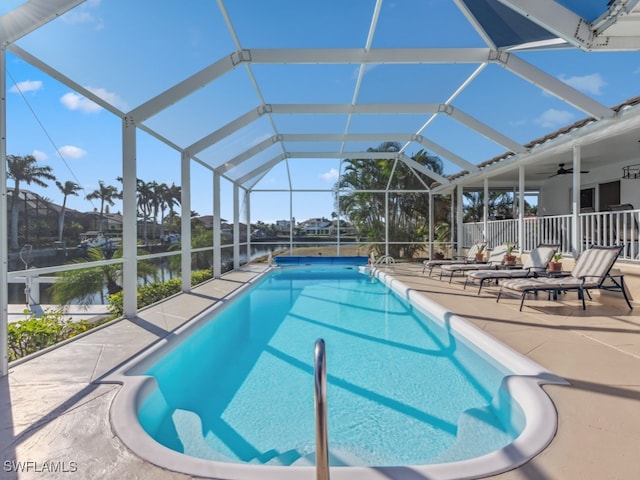 view of swimming pool with a lanai, ceiling fan, a water view, and a patio