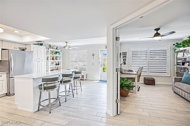 kitchen featuring stainless steel fridge, white cabinetry, a center island, and light hardwood / wood-style floors