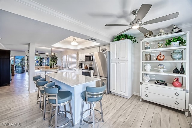 kitchen featuring a breakfast bar area, white cabinets, light hardwood / wood-style floors, and appliances with stainless steel finishes