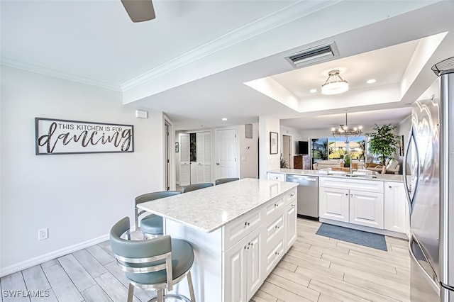 kitchen with a kitchen island, white cabinetry, a breakfast bar area, and appliances with stainless steel finishes