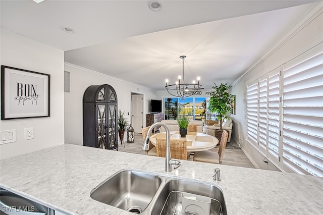 kitchen with light stone countertops, sink, a healthy amount of sunlight, crown molding, and light wood-type flooring