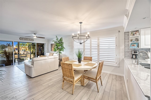 dining room with ornamental molding, ceiling fan with notable chandelier, light hardwood / wood-style floors, and a healthy amount of sunlight