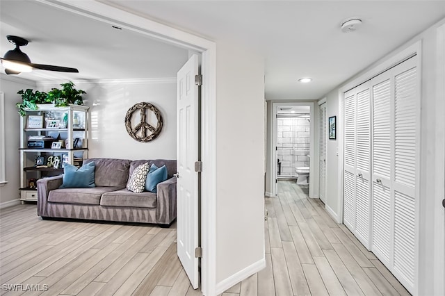 corridor with light hardwood / wood-style floors and ornamental molding