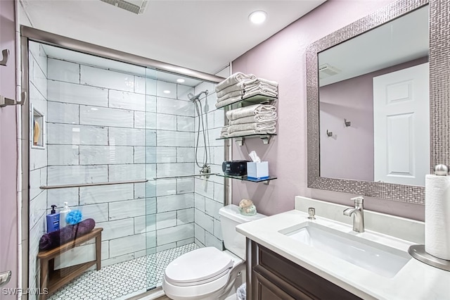 bathroom with tiled shower, vanity, and toilet