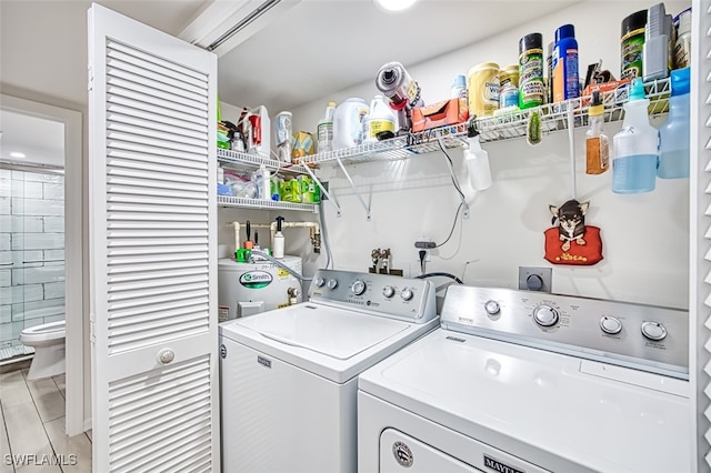 laundry area featuring electric water heater, light tile patterned flooring, and separate washer and dryer