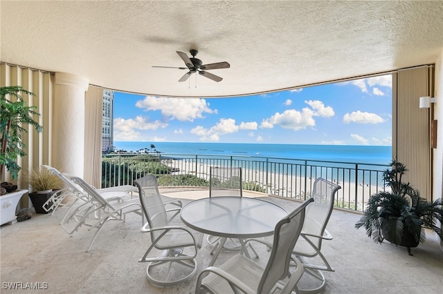 balcony with a beach view, a water view, and ceiling fan