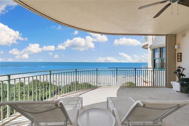 balcony with a beach view, a water view, and ceiling fan