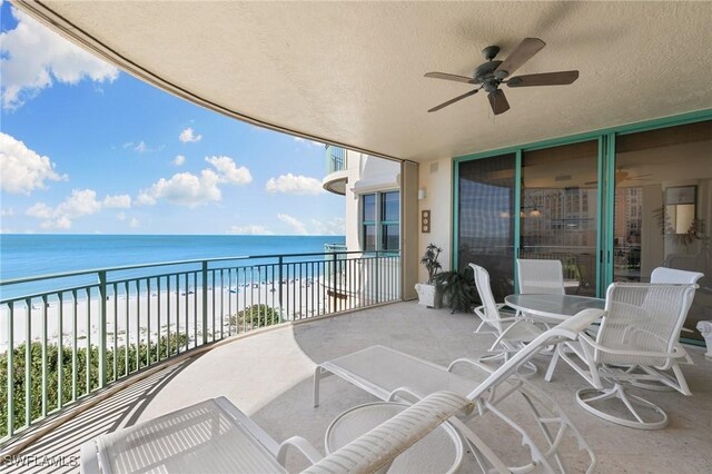 balcony featuring ceiling fan, a water view, and a view of the beach