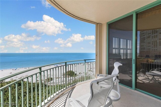 balcony with a water view and a view of the beach