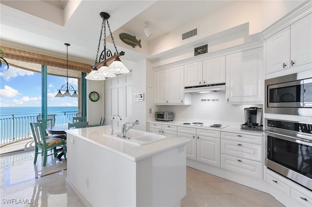 kitchen featuring appliances with stainless steel finishes, a water view, white cabinetry, and a center island with sink