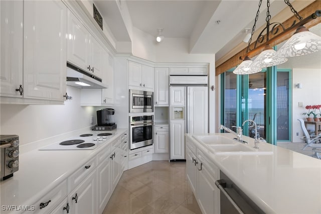 kitchen featuring built in appliances, pendant lighting, white cabinets, and sink