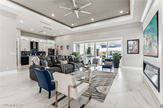 living room with a raised ceiling, ceiling fan, and beverage cooler