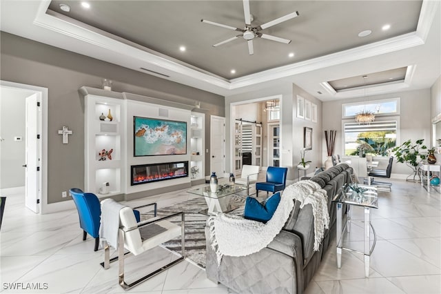 living room with ceiling fan with notable chandelier, a tray ceiling, and ornamental molding