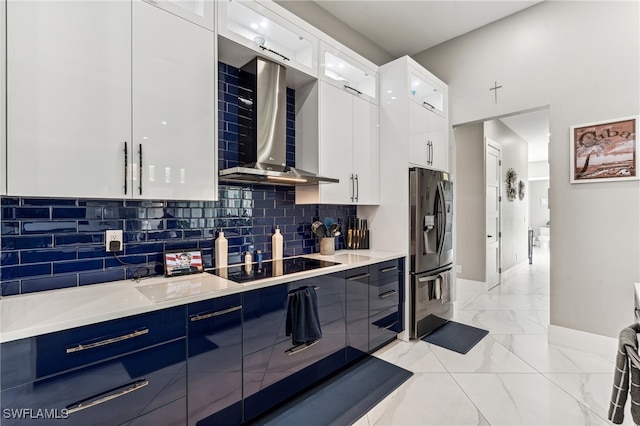 kitchen with white cabinets, wall chimney range hood, stainless steel refrigerator with ice dispenser, decorative backsplash, and black electric cooktop