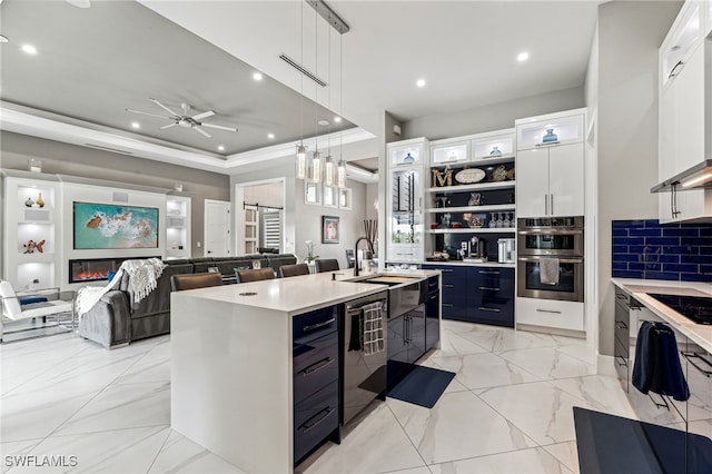 kitchen with pendant lighting, a center island with sink, white cabinets, sink, and decorative backsplash