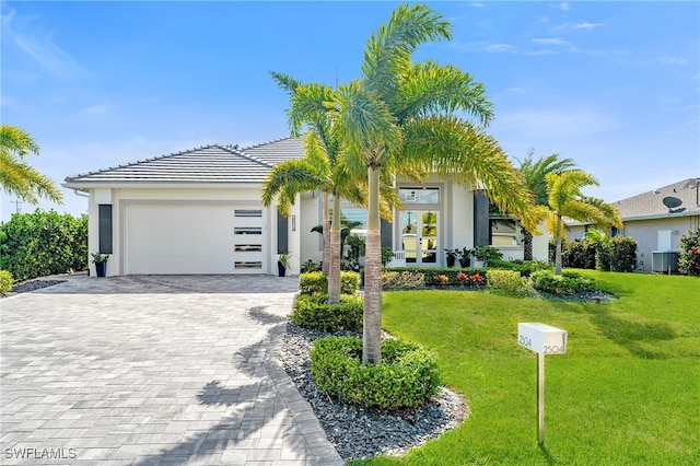 view of front of home with central AC, a front lawn, and a garage