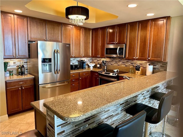 kitchen featuring decorative backsplash, appliances with stainless steel finishes, and a breakfast bar area