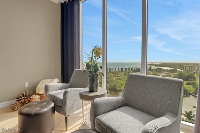 living area featuring baseboards, a water view, and tile patterned flooring