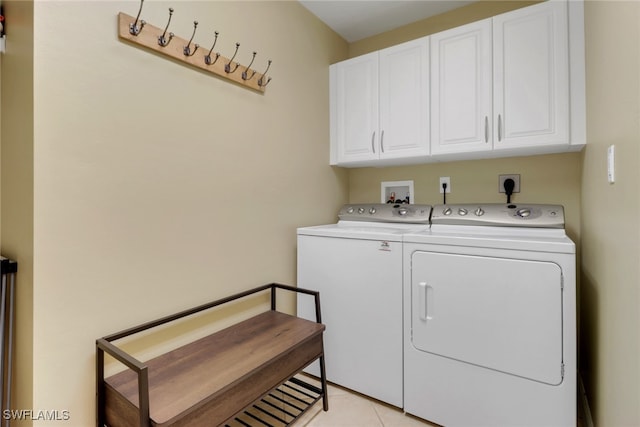 clothes washing area featuring light tile patterned floors, cabinet space, and washer and clothes dryer