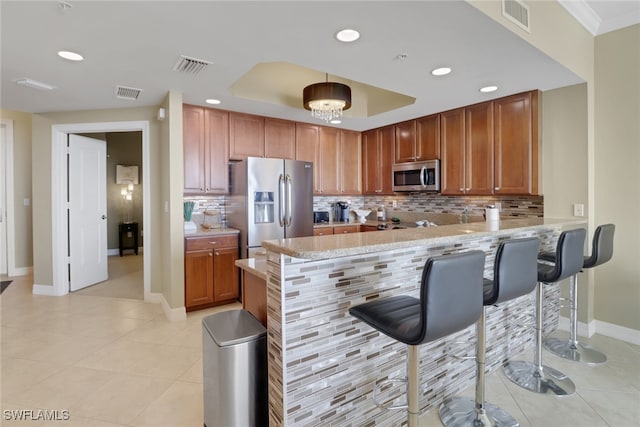 kitchen with visible vents, a peninsula, stainless steel appliances, and a tray ceiling