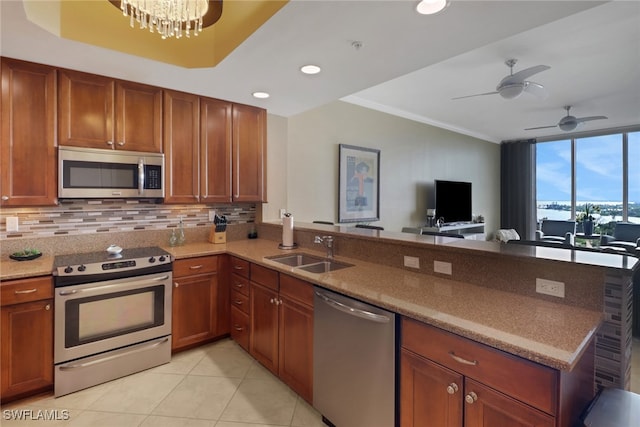 kitchen featuring light tile patterned floors, a peninsula, a sink, appliances with stainless steel finishes, and tasteful backsplash