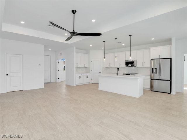 kitchen with white cabinets, ceiling fan, a kitchen island with sink, and appliances with stainless steel finishes