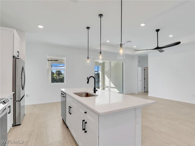 kitchen featuring sink, hanging light fixtures, an island with sink, white cabinets, and appliances with stainless steel finishes