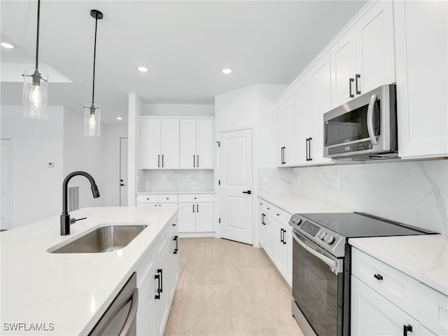 kitchen featuring sink, appliances with stainless steel finishes, tasteful backsplash, decorative light fixtures, and white cabinetry