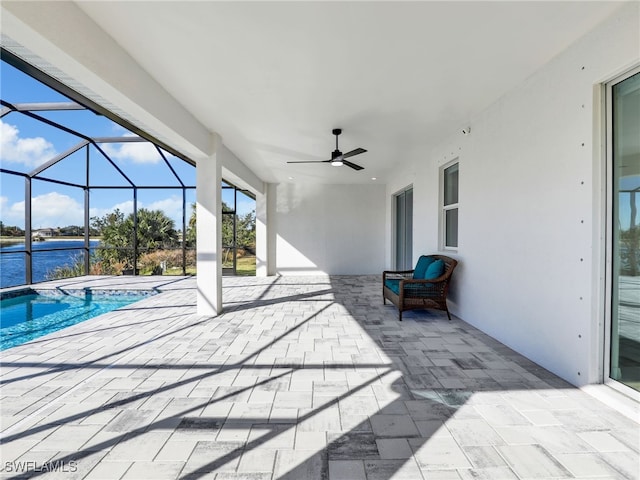 view of patio / terrace with a lanai, ceiling fan, a swimming pool with hot tub, and a water view