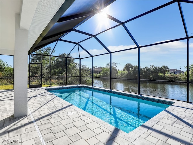 view of swimming pool with glass enclosure, a water view, and a patio