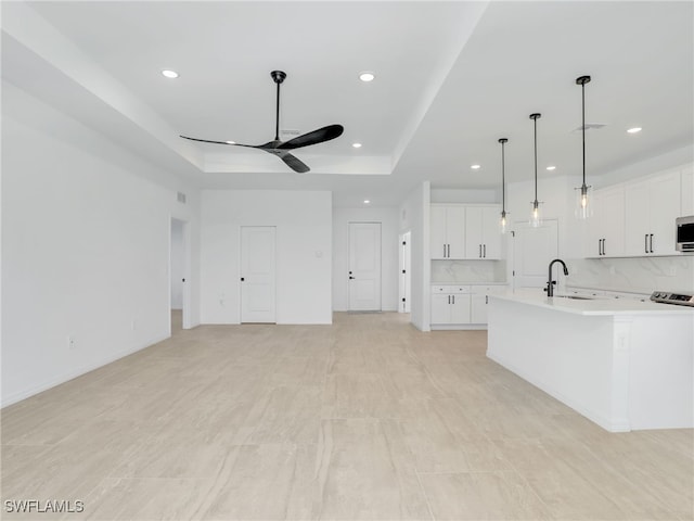 kitchen with white cabinets, a raised ceiling, hanging light fixtures, and sink