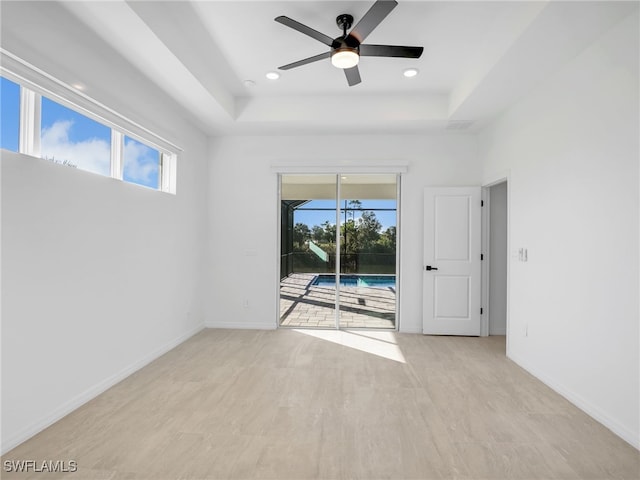 spare room featuring plenty of natural light, ceiling fan, and a tray ceiling