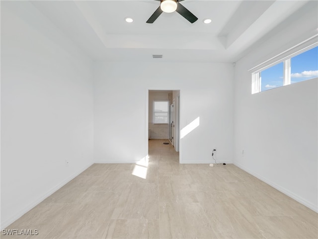 empty room featuring ceiling fan and a raised ceiling