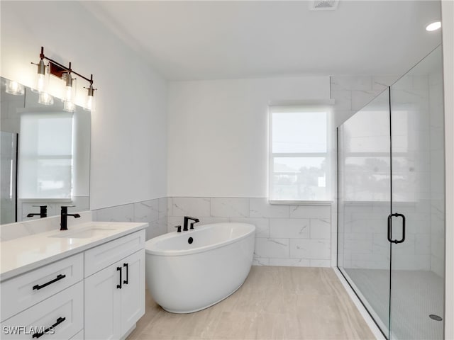 bathroom with plus walk in shower, vanity, tile patterned floors, and tile walls