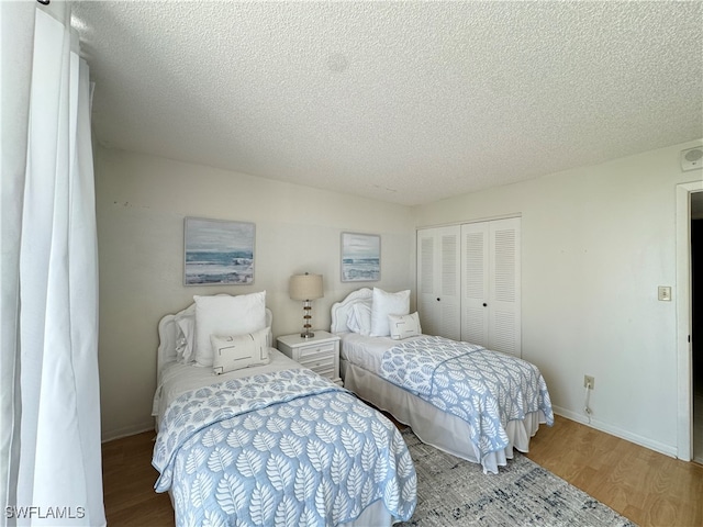 bedroom with a closet, wood-type flooring, and a textured ceiling