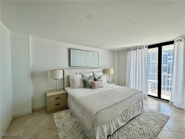 bedroom with access to outside, light tile patterned floors, and a textured ceiling