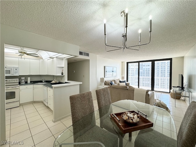 dining area with ceiling fan with notable chandelier, light tile patterned flooring, sink, and a textured ceiling