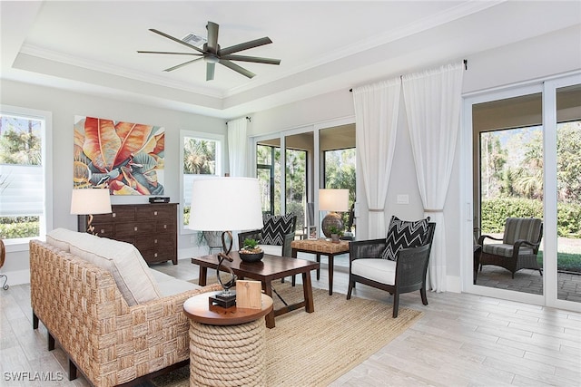 interior space featuring ceiling fan, a raised ceiling, ornamental molding, and light hardwood / wood-style flooring